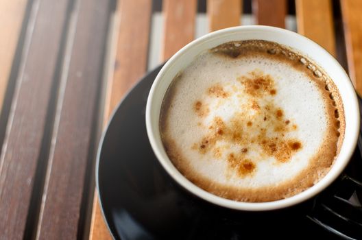 A Cup of Cappuccino Coffee on the horaizontal line brown wood table and ready to served and enjoy drink in the relaxing time with copy space.