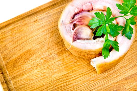 Pork belly with garlic and parsley on wooden board isolated on a white background.