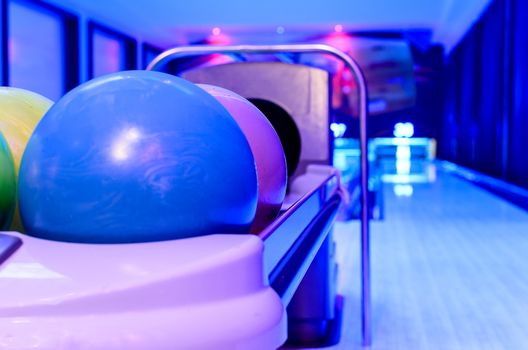 A Purple Bowling balls has ready for player to throwing ball on the wooden lane and in the bowling hall.