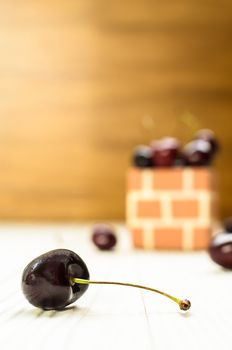 A Purple Cherry in front of cherry group on the wood table and brown wood background.