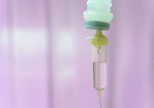 Close up saline IV drip for patient and Infusion pump in hospital with purple drape background..