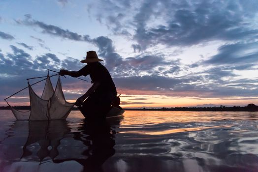 Silhouette of Fishermen throwing net fishing in sunset time at Wanon Niwat district Sakon Nakhon Northeast Thailand.