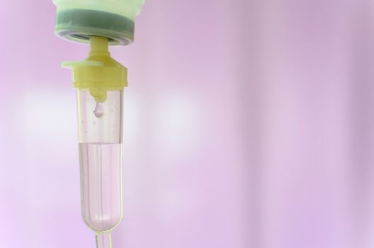 Close up saline IV drip for patient and Infusion pump in hospital with purple drape background..