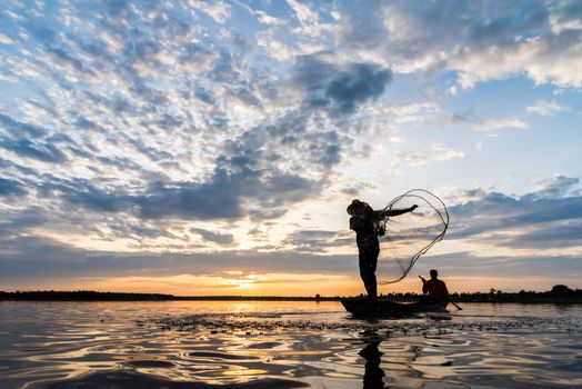 Silhouette of Fishermen throwing net fishing in sunset time at Wanon Niwat district Sakon Nakhon Northeast Thailand.