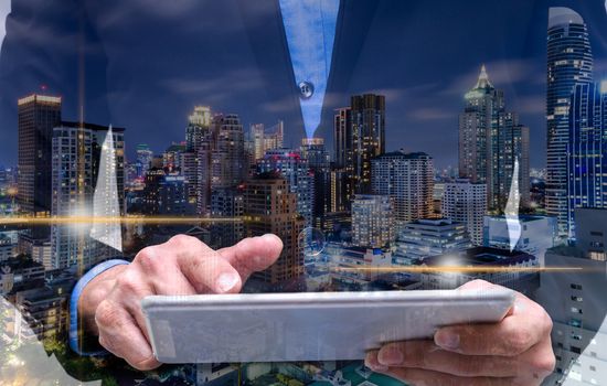 Double exposure of businessman using tablet with long exposure city.