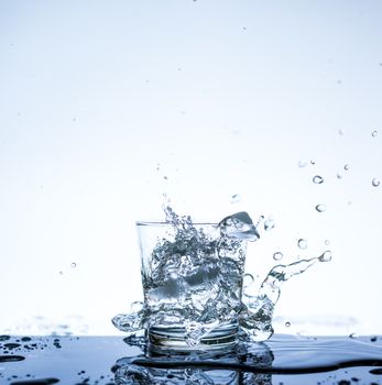 Water splashing in the glass with reflection on mirror.