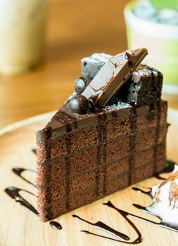 Chocolate Cake with wafer and whipped cream on wood plate has ready to served.