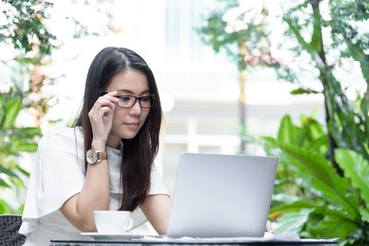 Beautiful asian attractive woman has working and typing on laptop computer for business marketing at coffee cafe in the morning with happy and relaxing time.