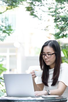 Beautiful asian attractive woman has holding and drinking a coffee before start working at coffee cafe in the morning with happy and relaxing time.