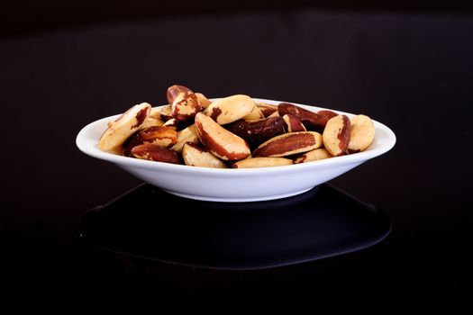 Brazil Nuts in a white plate on a black background