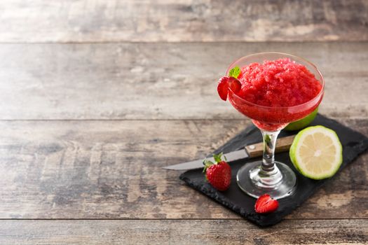 Strawberry margarita cocktail in glass on wooden table