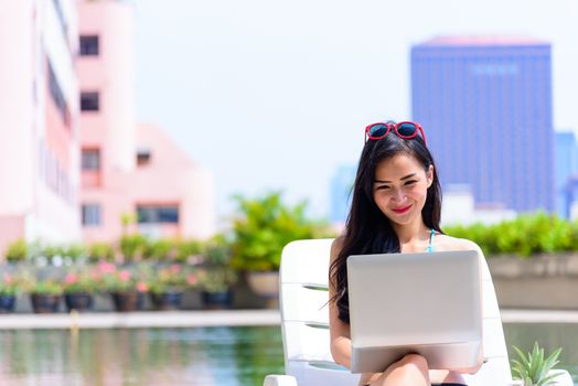 Sexy asian woman has working with laptop in the evening and sunset time with relaxing on vacation and holiday.