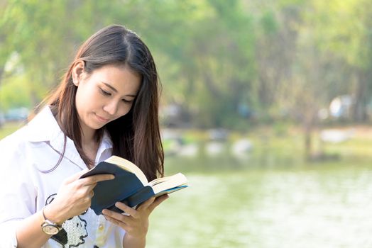 Beautiful asian woman reading a book at garden with happiness and relaxing in the evening with sunset time.