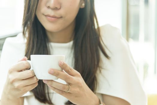 A coffee cup and beautiful asian married businesswoman in the morning with working and relaxing time.