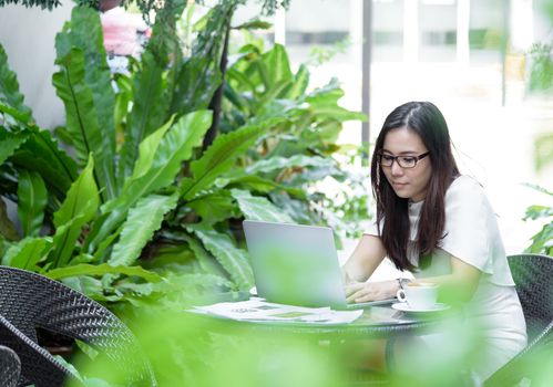 Beautiful asian attractive woman has working and typing on laptop computer for business marketing at coffee cafe in the morning with happy and relaxing time.