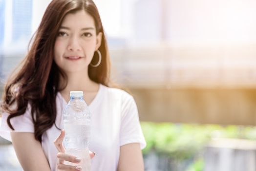 Asian beautiful woman has water drinking with city background in the morning.