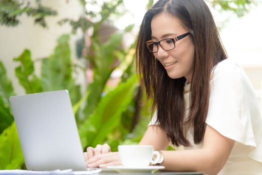 Beautiful asian attractive woman has working and typing on laptop computer for business marketing at coffee cafe in the morning with happy and relaxing time.