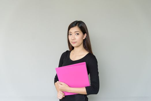 A businesswoman with black shirt and holding pink folder isolated on grey blackground.
