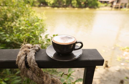 Hot mocha coffee or Cappuccino in the brown cup on the wooden table.