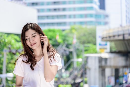 Asian beautiful woman tourist has music listening with headphone and happiness to travel.