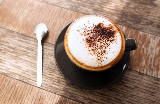 Hot mocha coffee or Cappuccino in the brown cup on the wooden table.