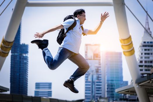 Asian businessman jumping with building and cityscape background.