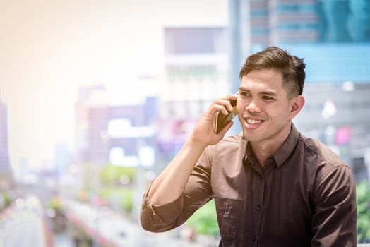 The asian businessman working and operation in outside office with building and city background.