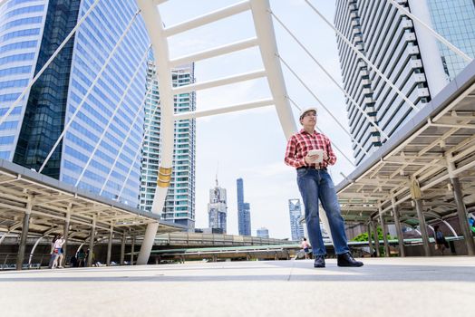 Asian business and engineer man with red scott shirt has planning and working for design buiding and city.