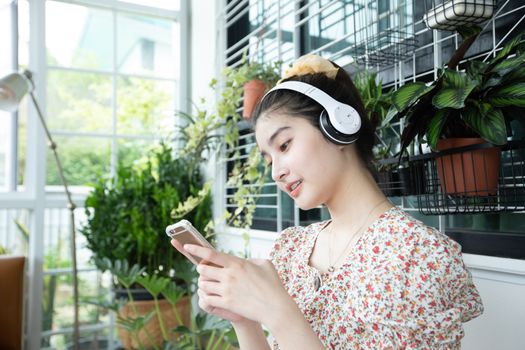 Asian women wearing headphones and using mobile phone and digital tablet for Listening to music and singing on a relaxing day at home