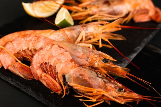 Raw shrimp langostino and lime on black stone plate background luxury restaurant menu image