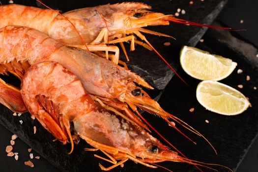 Raw shrimp langostino and lime on black stone plate background luxury restaurant menu image
