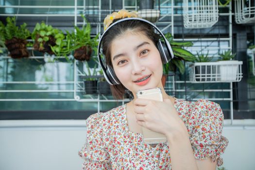 Asian women wearing headphones and using mobile phone and digital tablet for Listening to music and singing on a relaxing day at home