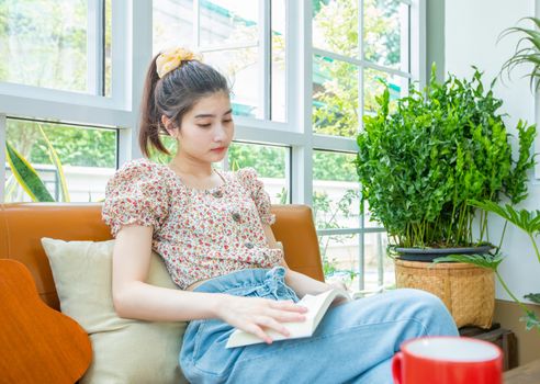 Asian women reading a book in the garden at home on a relaxing time