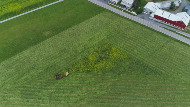 An aerial shot of an Amish farmer harvesting crop