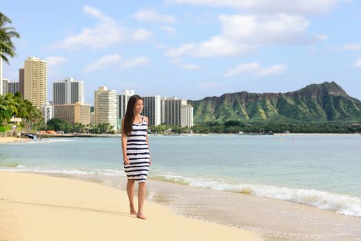 Waikiki beach Hawaii travel tourist woman relaxing walking on sand at sunset on famous beach stretch in Honolulu summer vacation destination in Oahu, Hawaii, USA.
