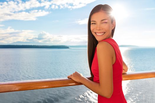 Happy cruise ship passenger outside on suite balcony enjoying luxury view of ocean in travel destination during summer. Beautiful Asian woman.