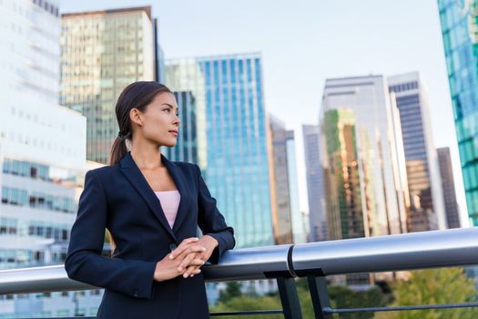 Happy business woman portrait of young female urban professional businesswoman in suit standing outside office buildings cross-armed. Confident successful multicultural Chinese Asian / Caucasian woman
