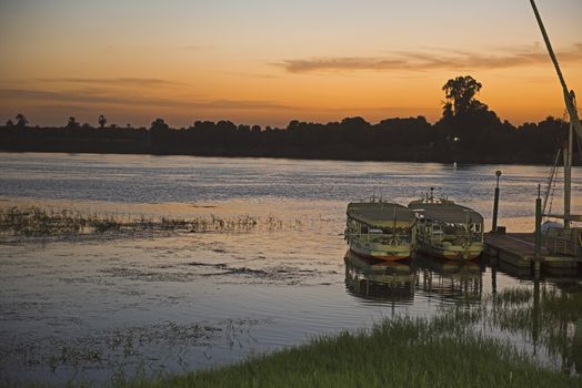 Traditional Egyptian felluca sailing boat on river Nile moored at jetty in dusk sunset