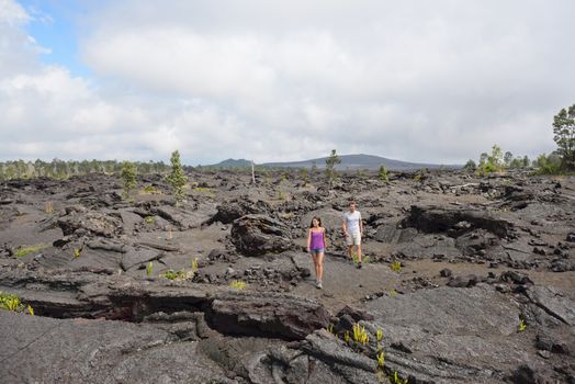 Hawaii destination travelers couple hiking in volcanic rocks on Kilauea volcano in Big island of Hawaii.