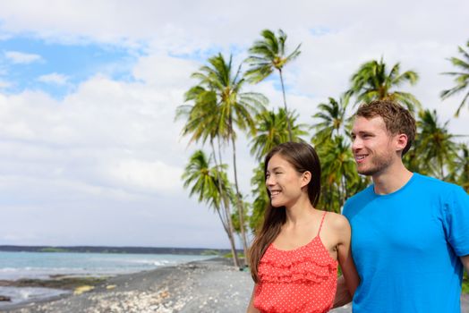 Interracial couple on Hawaii holiday enjoying view of ocean from black sand volcanic beach on Big Island of Hawaii, hawaiian vacation destination.