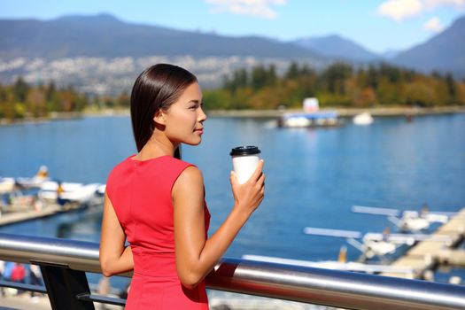 Asian businesswoman drinking coffee enjoying view of Vancouver harbor in city center. Business lifestyle.