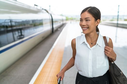 Happy Asian traveler smiling going on train travel in business class. Beautiful woman with hand luggage leaving on luxury transport. Businesswoman commuting to work in the morning.