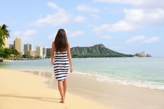 Waikiki beach vacation woman relaxing walking on sand at sunset. Honolulu travel destination in Oahu, Hawaii.