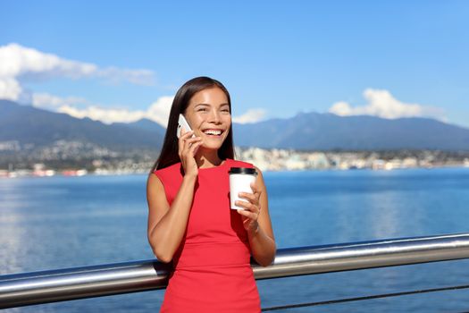 Happy business woman talking on the phone while drinking coffee outdoor in summer, landscape of Vancouver in background. Businesswoman work city lifestyle.