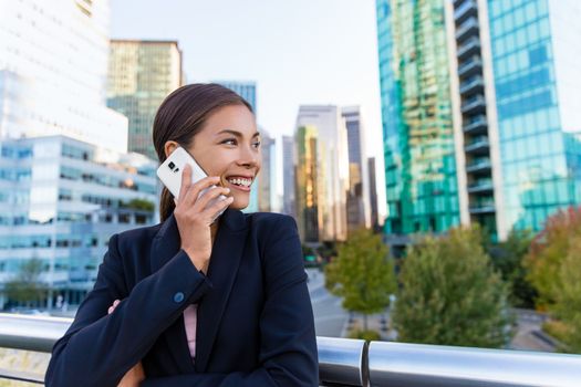 Smart casual wear blazer woman calling on mobile phone in city business district. Confident happy young businesswoman talking on smartphone outdoors. Urban professional in Vancouver, Canada.
