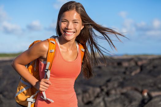 Happy backpacking girl tourist on travel adventure. Young hiking Asian backpacker woman hiker walking on lava rocks in Hawaii near Kilauea volcano. Active lifestyle.
