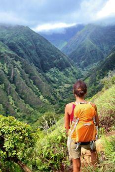 Hiker woman backpacker hiking with backpack in Hawaii mountains on Waihee ridge trail, Maui, USA. Hiker girl walking in tropical forest nature landscape.