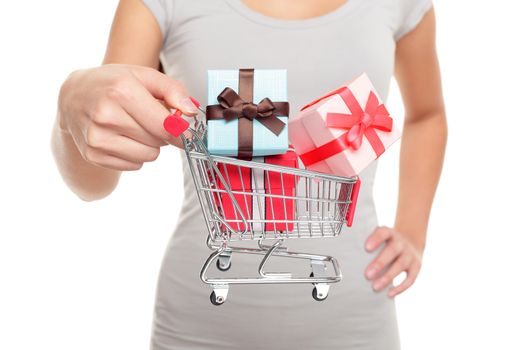 Miniature shopping cart with Christmas gifts for holiday shopping on boxing day or black friday. Closeup of woman hands holding mini toy object for spending concept.