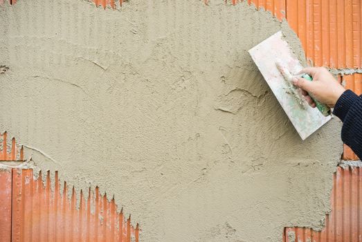 Industrial plasterer at plaster work of brick wall on construction site