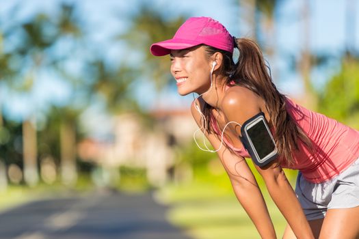 Happy summer running woman runner listening to music on phone sports armband with touchscreen and headphones earphones on city street, active lifestyle. Fitness Asian girl ready for jogging.